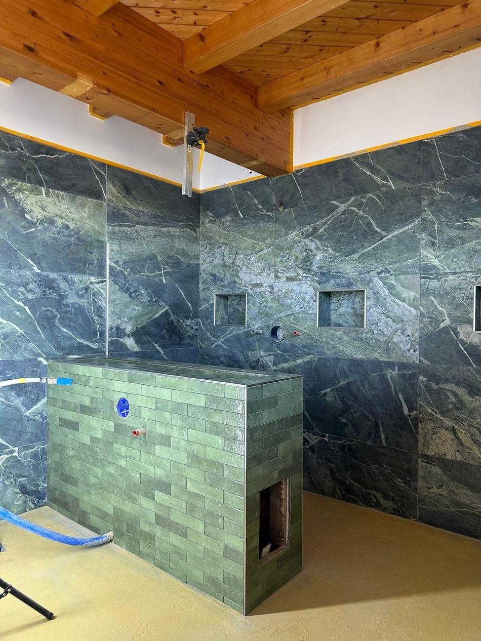Badezimmer mit grünen Marmorfliesen und gemauertem Waschtisch, ausgeführt von Maai Bautechnik