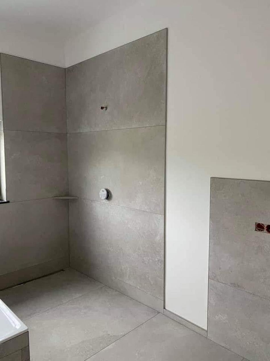 Fertig gefliestes Badezimmer in heller Steinoptik, ausgeführt von Maai Bautechnik