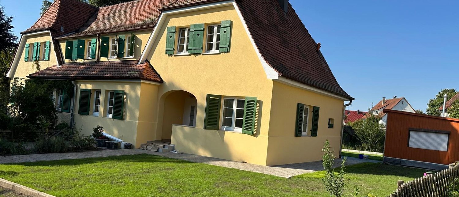 Saniertes Wohnhaus mit neuer Fassade und angelegtem Garten, ausgeführt von Maai Bautechnik