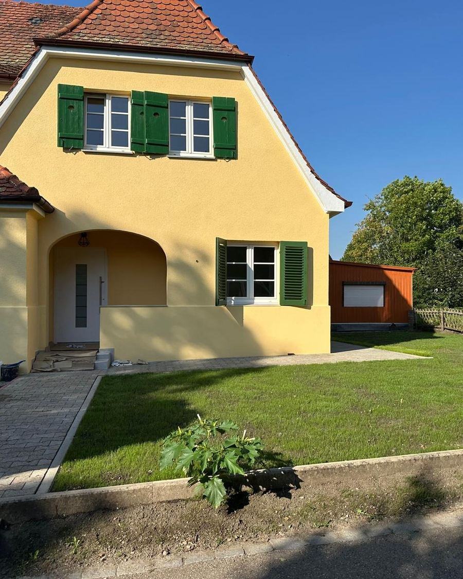 Sanierte Hausfassade mit neuem Putz und grünen Fensterläden, ausgeführt von Maai Bautechnik